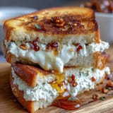 A close-up of the Goat Cheese Grilled Cheese with Honey & Chili Flakes shows melted cheese oozing between crisp bread.  