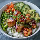 Colorful Baked Salmon Rice Bowl with avocado, edamame, and carrots drizzled with sriracha mayo for a quick dinner.  