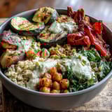 Close-up of Mediterranean Buddha Bowl Meal Prep featuring golden roasted eggplant cubes, tender steamed kale, and colorful bell peppers nestled on nutty bulgur pilaf with pistachios.
