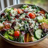 Colorful Greek Salad Bowl featuring chopped romaine, crunchy cucumbers, briny olives, and creamy feta, ready to serve.  