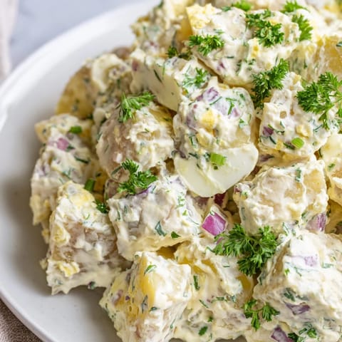 A bowl of fresh potato salad with diced celery, onions, and bright parsley, ready to enjoy.