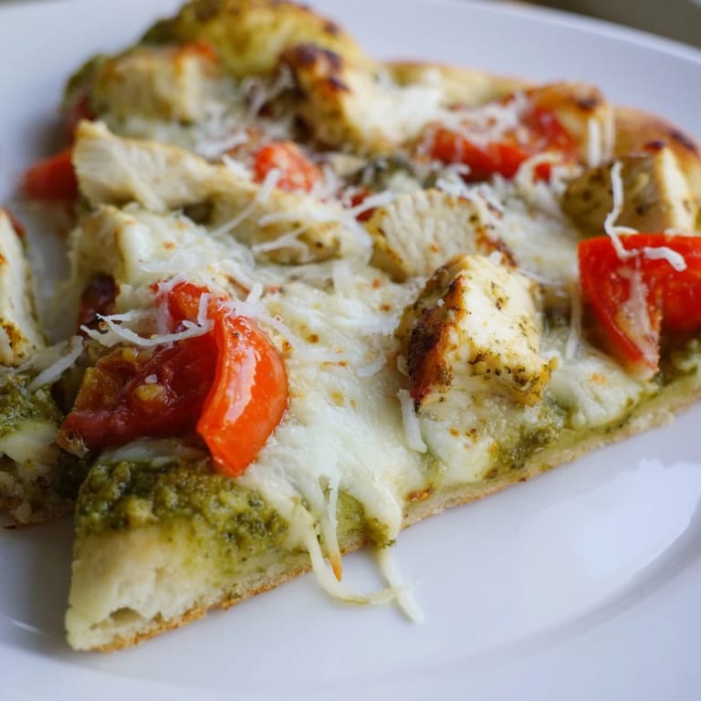 Golden-brown thin-crust Chicken Pesto Pizza topped with seasoned chicken, vibrant basil pesto, and bubbling cheese, ready to serve for a family dinner.