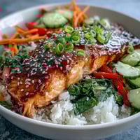 Flaky soy-ginger glazed salmon rests on fluffy rice in this vibrant Asian-Inspired Salmon Bowl, garnished with fresh lime and sesame seeds.