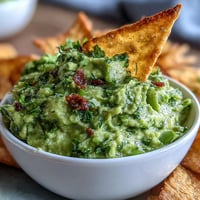 Creamy edamame guacamole served with golden, crisp pita chips for a fresh, protein-packed snack.